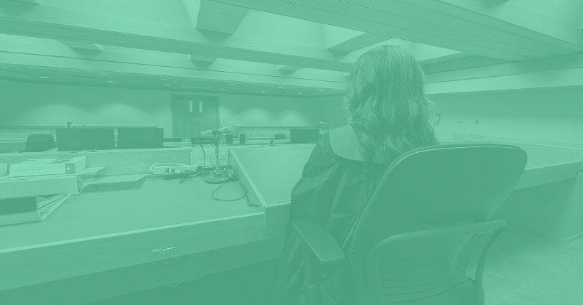 View of woman judge from behind as she sits facing the courtroom.